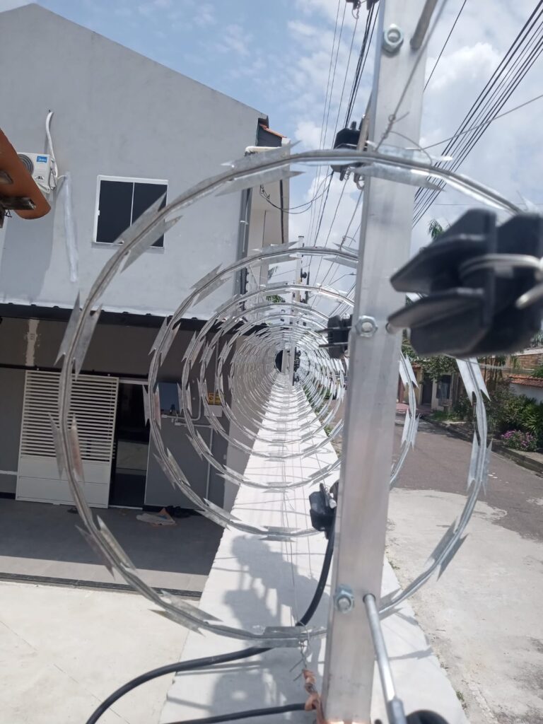 Vista por dentro da espiral de concertina, fixada nas hastes de alumínio com isoladores ao longo de todo o muro